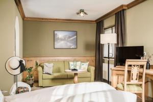 a bedroom with a bed and a couch and a tv at Hotel Sieghard Zillertal in Mayrhofen