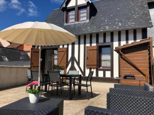 Un patio con una mesa y sillas y una sombrilla. en La terrasse honfleuraise, en Honfleur