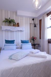 1 dormitorio con 1 cama blanca grande con almohadas azules en Häxaris Casa Boutique by Florentia Homes en Granada
