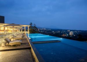 a swimming pool with a view of a city at night at Swiss-Belresort Dago Heritage in Bandung