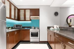 a kitchen with wooden cabinets and a blue wall at Ascott Makati in Manila