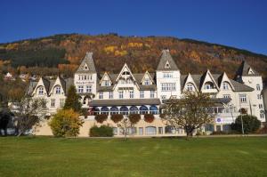 a large white building with a mountain in the background at Fleischer's Hotel in Vossevangen