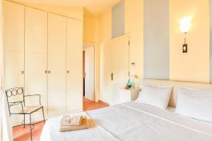 sypialnia z dużym białym łóżkiem i krzesłem w obiekcie Villa Casa Del Sol with private pool w mieście Sunion +19 zdjęć