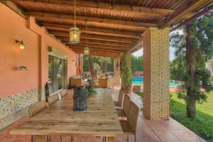 a wooden table and chairs on a patio with a roof at Villa Casa Del Sol with private pool in Sounio