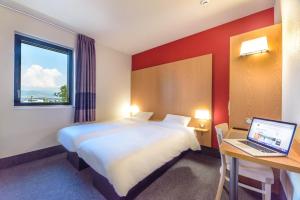 une chambre d'hôtel avec un lit et un ordinateur portable sur un bureau dans l'établissement B&B HOTEL Colmar Expo, à Colmar