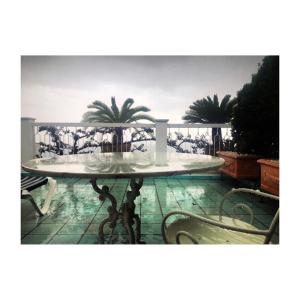 una mesa en un balcón con 2 palmeras en Hotel Bellevue Suite en Amalfi