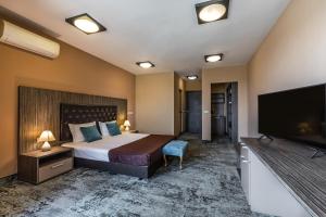 a hotel room with a bed and a flat screen tv at Plaza Hotel Plovdiv - Free Parking in Plovdiv