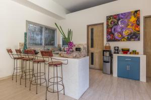 a kitchen with a counter with chairs and a painting at Villa Purple in Legian