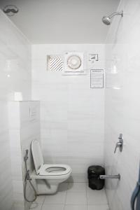 a white bathroom with a toilet and a shower at Moustache Varanasi in Varanasi