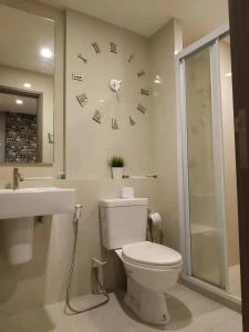 a bathroom with a toilet and a clock on the wall at the base condo in Pattaya Central