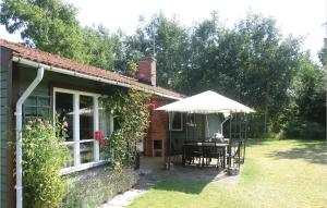 a house with a table and an umbrella on a yard at Nice Home In Nybrostrand With 3 Bedrooms And Wifi in Kabusa