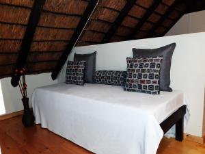 uma cama num quarto com almofadas em Little Tree Loft em Uitenhage