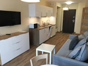 a living room with a blue couch and a kitchen at Apartament Silence Triventi Agat in Karpacz