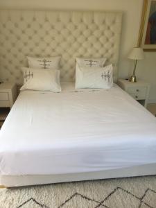 a large white bed with a large headboard and pillows at Villa Louise-Rose in Villeneuve-Loubet