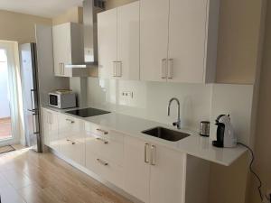 a white kitchen with a sink and a microwave at Casita en Granada in Granada