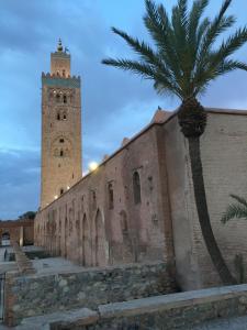 マラケシュにあるRiad Le Marrakech Berrimaの時計塔とヤシの木のある建物