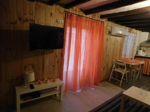 un soggiorno con tenda arancione e TV di La Casita, Apartamento Completo a Los Navalucillos