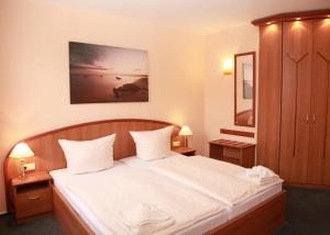 a bedroom with a large bed with white sheets and pillows at Hotel Bertramshof in Wismar