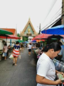 Una mujer parada en un mercado mirando su billetera en 59Indyhouse, en Bangkok