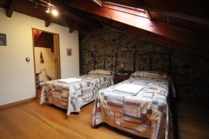 two beds in a room with a stone wall at La Solana de Babia in Torrestío