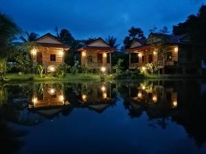 a resort with lights on the water at night at The Hidden Oasis Bungalows in Kampot