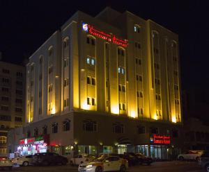 a lit up building with cars parked in front of it at Samara Hotel in Muscat