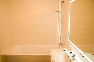 a bathroom with a white tub and a sink at Apartament Verde in Łódź