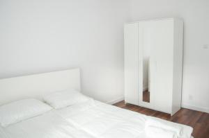 a white bedroom with a white bed and a mirror at Apartament Verde in Łódź