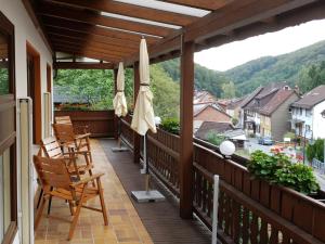a balcony with chairs and umbrellas overlooking a town at Haus Am Waldesrand in Herzberg am Harz