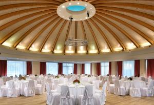 una sala da ballo con tavoli e sedie bianchi e un grande soffitto di UNAHOTELS Expo Fiera Milano a Pero