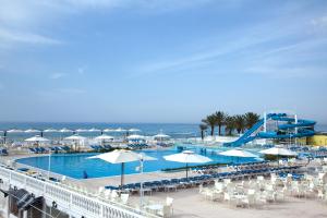 una piscina con sillas y sombrillas y el océano en Samira Club Family and couples only, en Hammamet