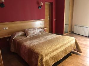 a bedroom with a bed and a red wall at Hotel Rural El Alberche in Burgohondo