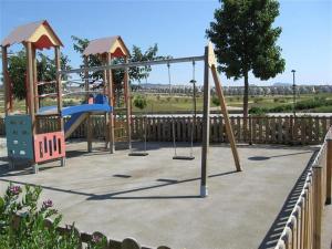 ein Spielplatz mit drei Schaukeln und einer Rutsche in der Unterkunft gelijkvloers appartement Corvera Golf & Country Club in Corvera