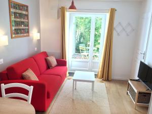a living room with a red couch and a window at Les gîtes du Clos Saint-Martin in Maule