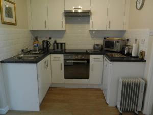 a kitchen with white cabinets and a sink and a microwave at Bespoke Chalet 214, walk to the beach & close to Norfolk broads - pet friendly! in Great Yarmouth