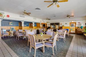 OYO Hotel Tyler Lindale في تايلر: غرفة طعام بها طاولات وكراسي ومراوح سقف