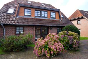 a house with two flowering bushes in front of it at Robben Hüs in Westerland