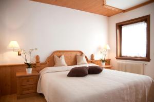 a bedroom with a bed with white sheets and a window at Residence Peniè in San Vito di Cadore