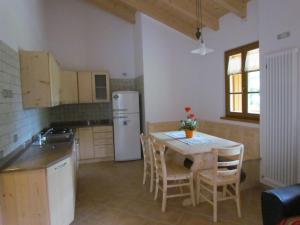 a kitchen with a table with chairs and a refrigerator at Agritur Maso Bornie in Grauno
