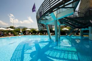 a swimming pool with a blue chair and blue umbrellas at Hotel Poseidon in Terracina