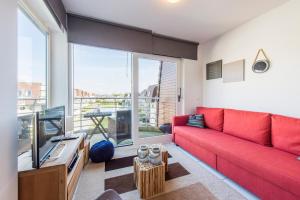 a living room with a red couch and a large window at Modern Apartment with Terrace & public Pool in Bredene