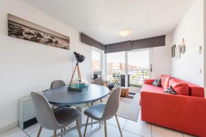 een woonkamer met een rode bank en een tafel en stoelen bij Modern Apartment with Terrace & public Pool in Bredene