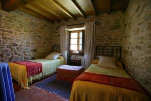 2 camas en una habitación con una pared de piedra en A Parada Das Bestas, en Pidre