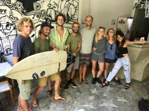 a group of people posing for a picture with a surfboard at Stellar Capsules in Seminyak
