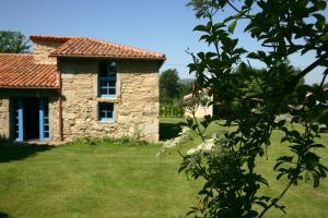 una casa in pietra in un campo con un albero di A Parada Das Bestas a Pidre