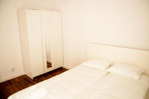 Habitación blanca con cama y espejo en Apartament Blu, en Łódź