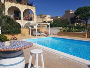 a swimming pool with a table and stools next to a house at Villa Ceni - Appartamenti con camere, cucina, wc e terrazza sul mare in villa con piscina, giardino e parcheggio in Marinella di Selinunte