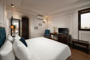 Dormitorio con cama, escritorio y TV en Maya Boutique Hotel & Spa, en Hanói