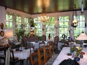 a dining room with tables and chairs and windows at Antiquitäten Café Schwarmstedt in Schwarmstedt