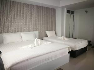 two beds in a hotel room with white sheets at Phimai Residence in Phimai